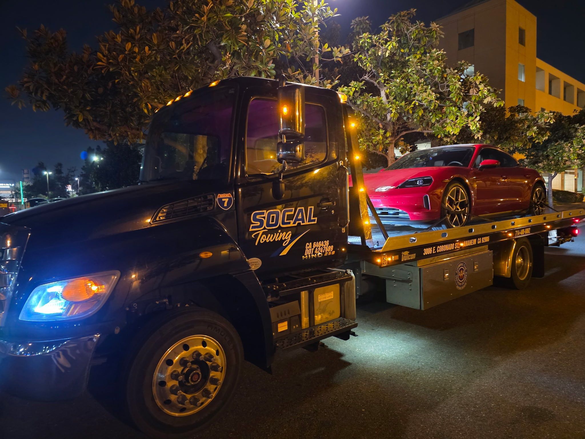 SoCal Towing flatbed carrying a Porsche Taycan at night