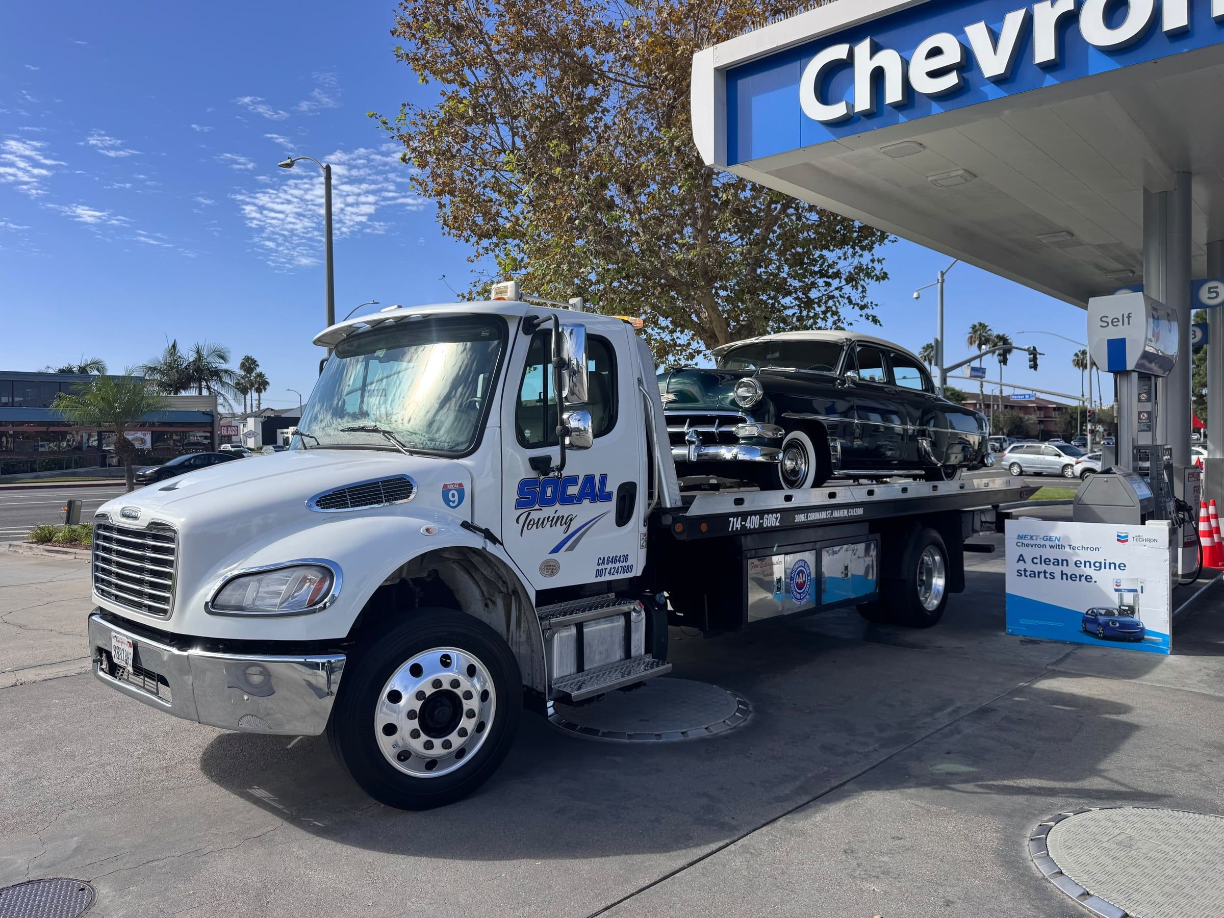 Classic sedan on a SoCal Towing flatbed at a gas station